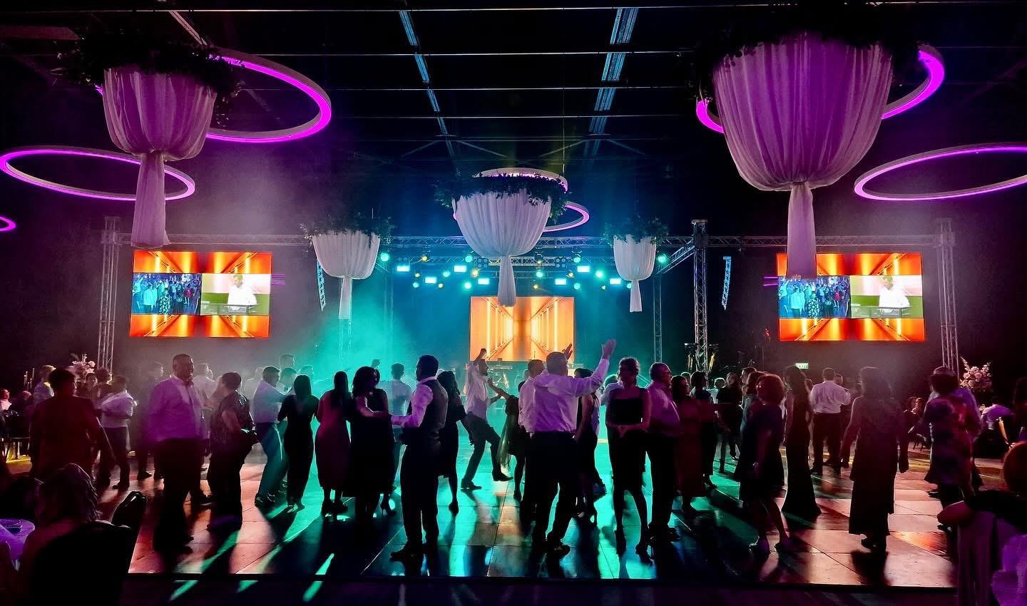 Invitați pe ringul de dans, cu lumini mov și verde și ecrane LED în sală