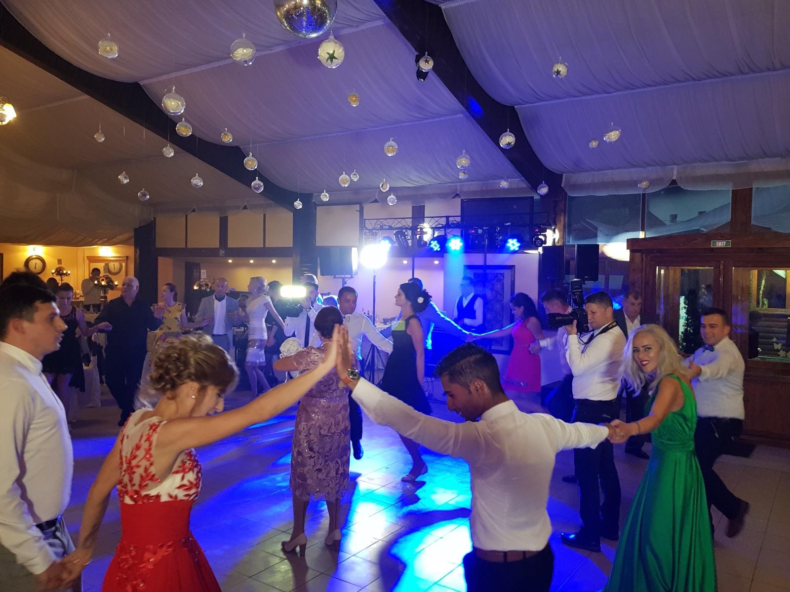 Invitați dansând hora la o nuntă cu lumini albastre